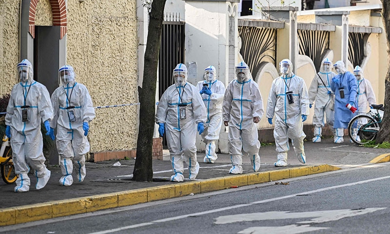 Health workers wearing protective gear walk to a compound to test residents for Covid-19 in Shanghai on Wednesday. &mdash; AFP