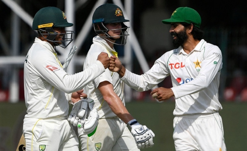 Pakistan's Fawad Alam (R) congratulates Australia's Usman Khawaja (L) after he scored a century as Australia's Steve Smith watches during the fourth day of the third and final Test match between Pakistan and Australia at the Gaddafi Cricket Stadium in Lahore on Thursday. — AFP