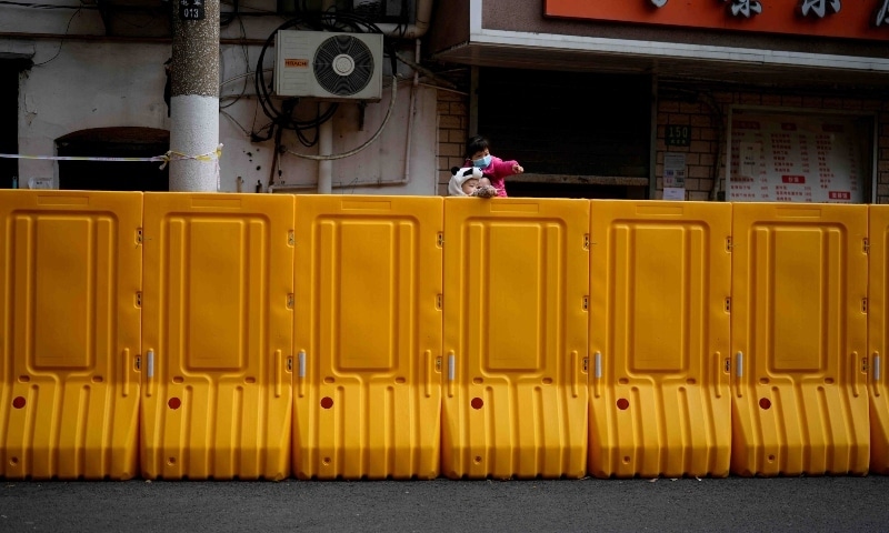 A man and two children look over a barrier of an area under lockdown amid the coronavirus pandemic in Shanghai on March 26. &mdash; Reuters