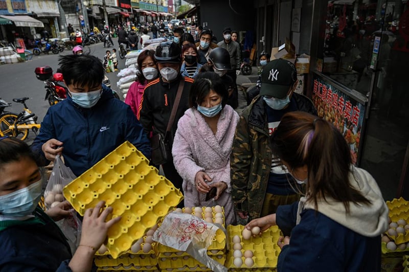 People queue to buy eggs next to a market in Yangpu district, in Shanghai on March 28. &mdash; AFP