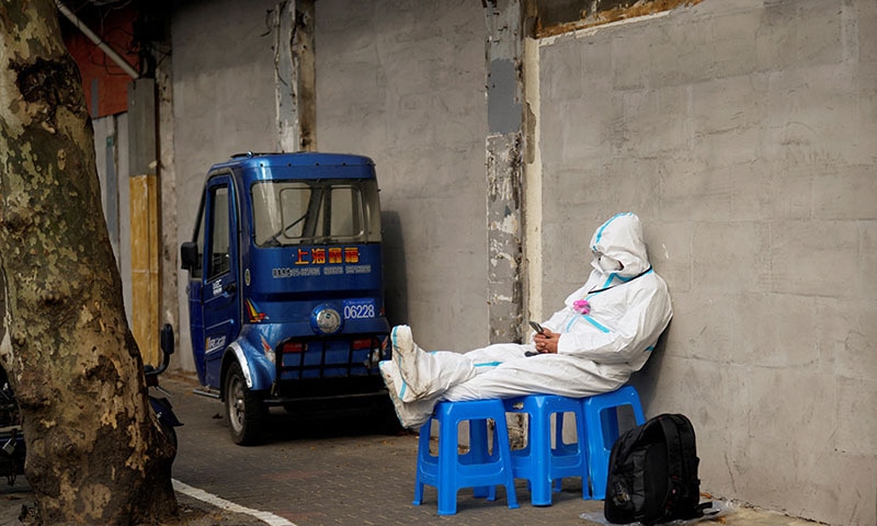 A worker in a protective suit sits on plastic stools following the coronavirus outbreak in Shanghai, China on Wednesday. &mdash; Reuters