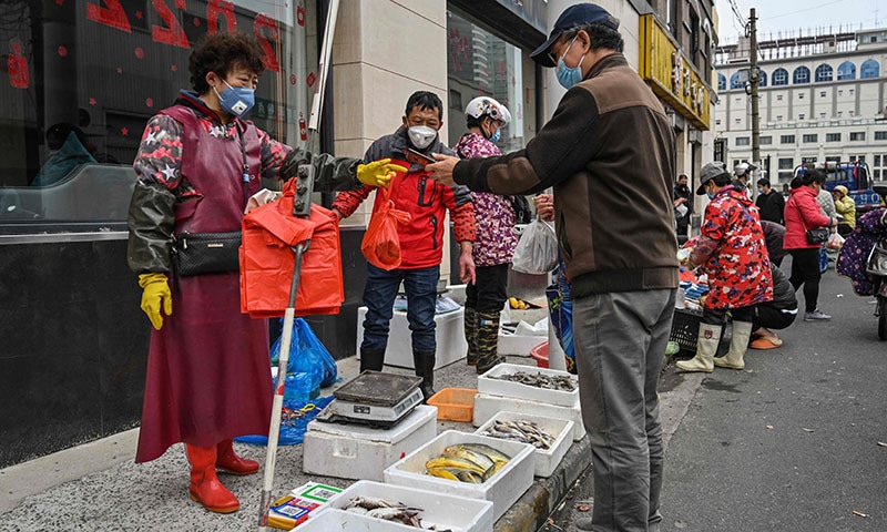 A man buys fish on a street next to a local market in Jing'an district, in Shanghai on Thursday. &mdash; AFP