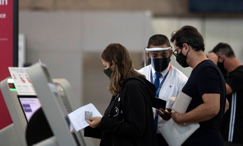 In this file photo taken on April 13, 2021, travellers are assisted by an airport employee at the boarding area of Galeao International Airport in Rio de Janeiro, Brazil. — AFP