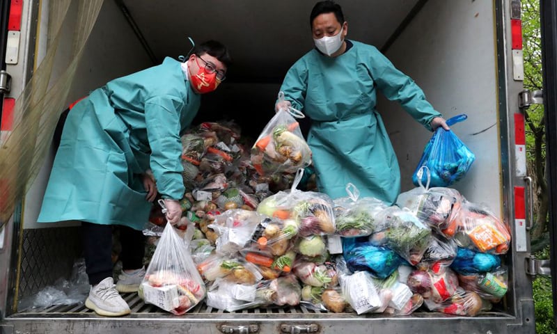 Workers wearing protective gear sort bags of vegetables and groceries on a truck to distribute them to residents at a residential compound during a Covid-19 lockdown in Shanghai. — Reuters