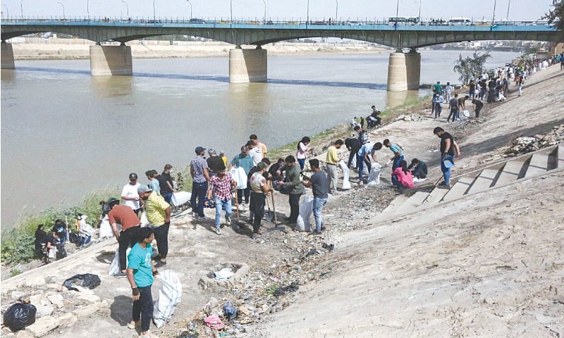 Baghdad: Volunteers take part in a clean-up campaign on the bank of the Tigris river in the Iraqi capital’s Adhamiyah district.—AFP