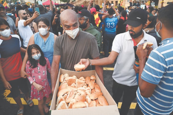 A MAN gives free food to demonstrators as they take part in a protest against the economic crisis at the entrance of the president’s office in Colombo.—AFP
