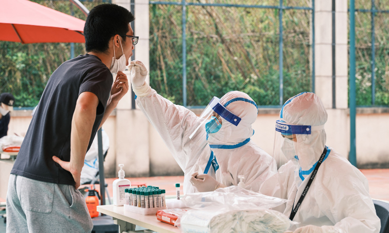 A health worker wearing personal protective equipment conducts a swab test for Covid-19 in a compound during a lockdown in Pudong district in Shanghai on Tuesday. &mdash; AFP