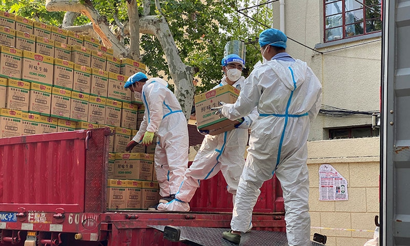 People in protective suits unload boxes labeled soy sauce from a truck, following the coronavirus outbreak in Shanghai, China on Thursday. &mdash; Reuters