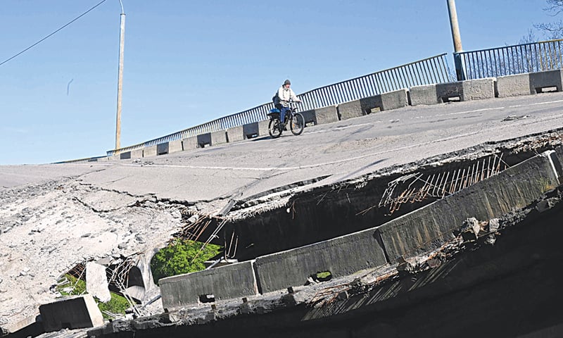 A MAN rides his bicycle over a heavily damaged bridge in a village near Russian-controlled Kharkiv on Thursday.—AFP