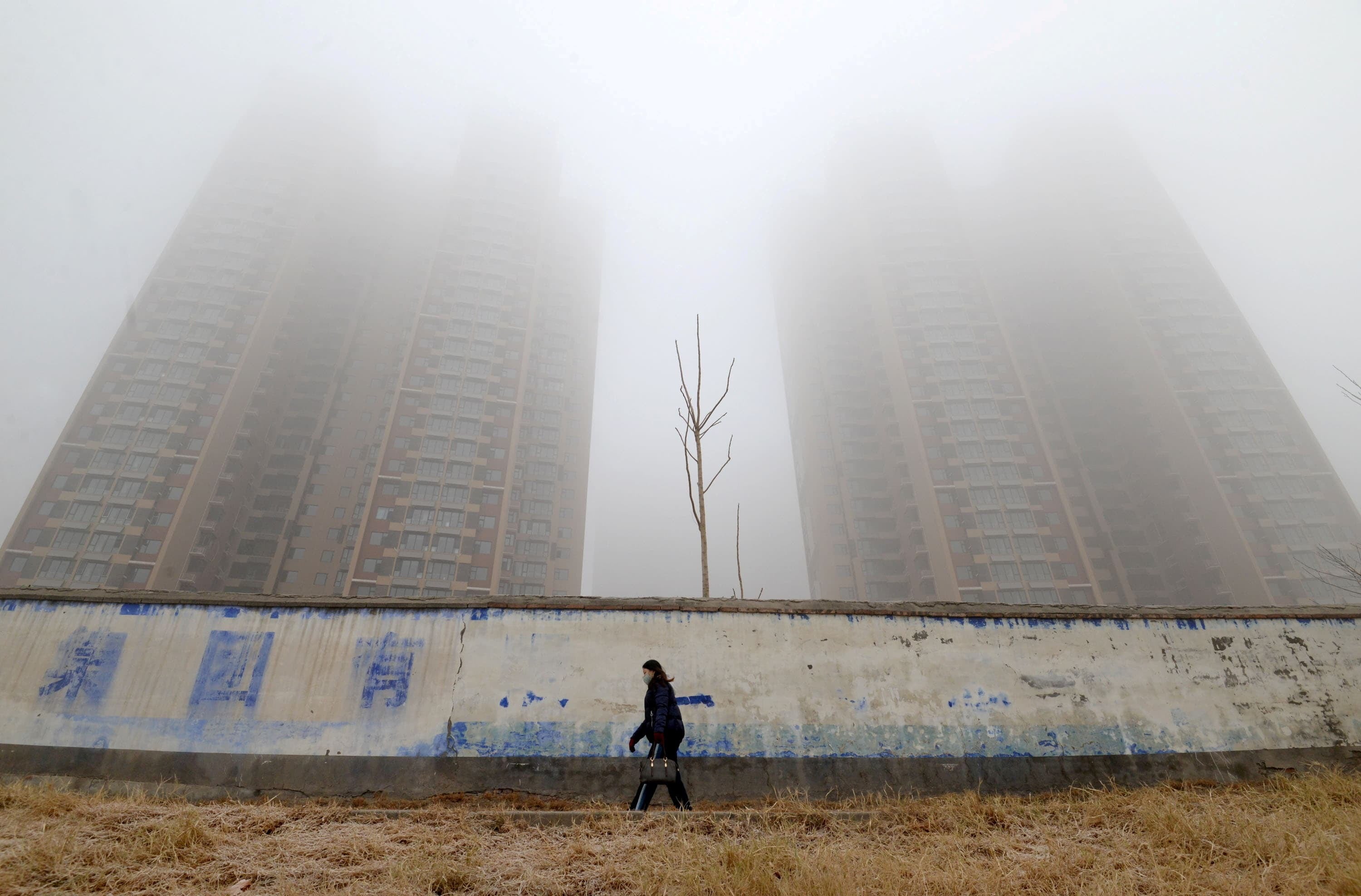 A woman wearing a mask walks past buildings on a polluted day in Handan, Hebei province, China. — Reuters/File