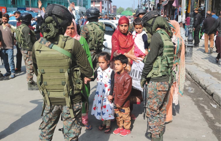 Female paramilitary troopers search a woman’s bag during a random operation at a Srinagar market