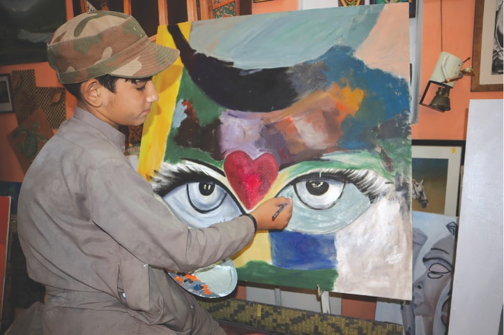 A boy gives the final touch to his painting