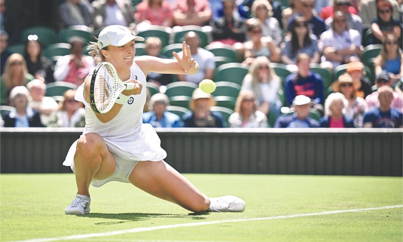 LONDON: Poland’s Iga Swiatek hits a return to Jana Fett of Croatia during their first-round match at Wimbledon on Tuesday.—AFP