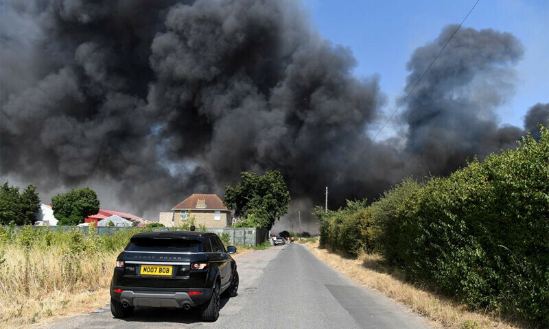 A car drives near a fire that burns during a heatwave, in east London, Britain, July 19, 2022.—Reuters/Tony O’Brien A car drives near a fire that burns during a heatwave, in east London, Britain, July 19, 2022.—Reuters/Tony O’Brien
