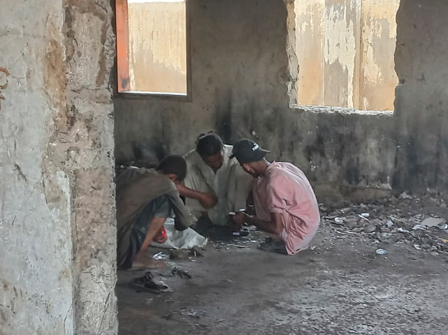 Three men using drugs in an abandoned government building in Rehri Goth