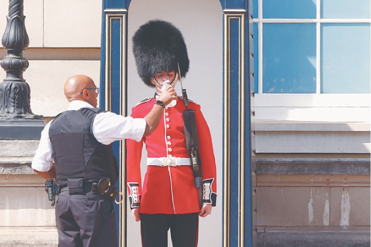 A MEMBER of the Queen’s Guard is given water to drink outside Buckingham Palace in London, amid sweltering temperatures.—Reuters