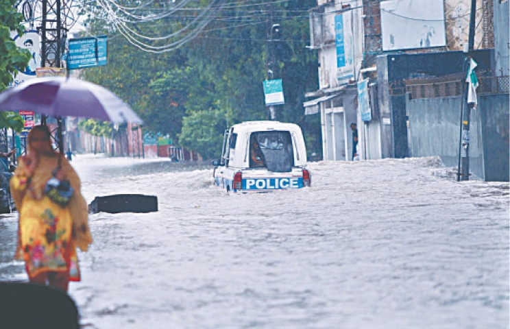 RAWALPINDI: A police mobile struggles to get through accumulated rainwater after heavy rains lashed the city.—APP