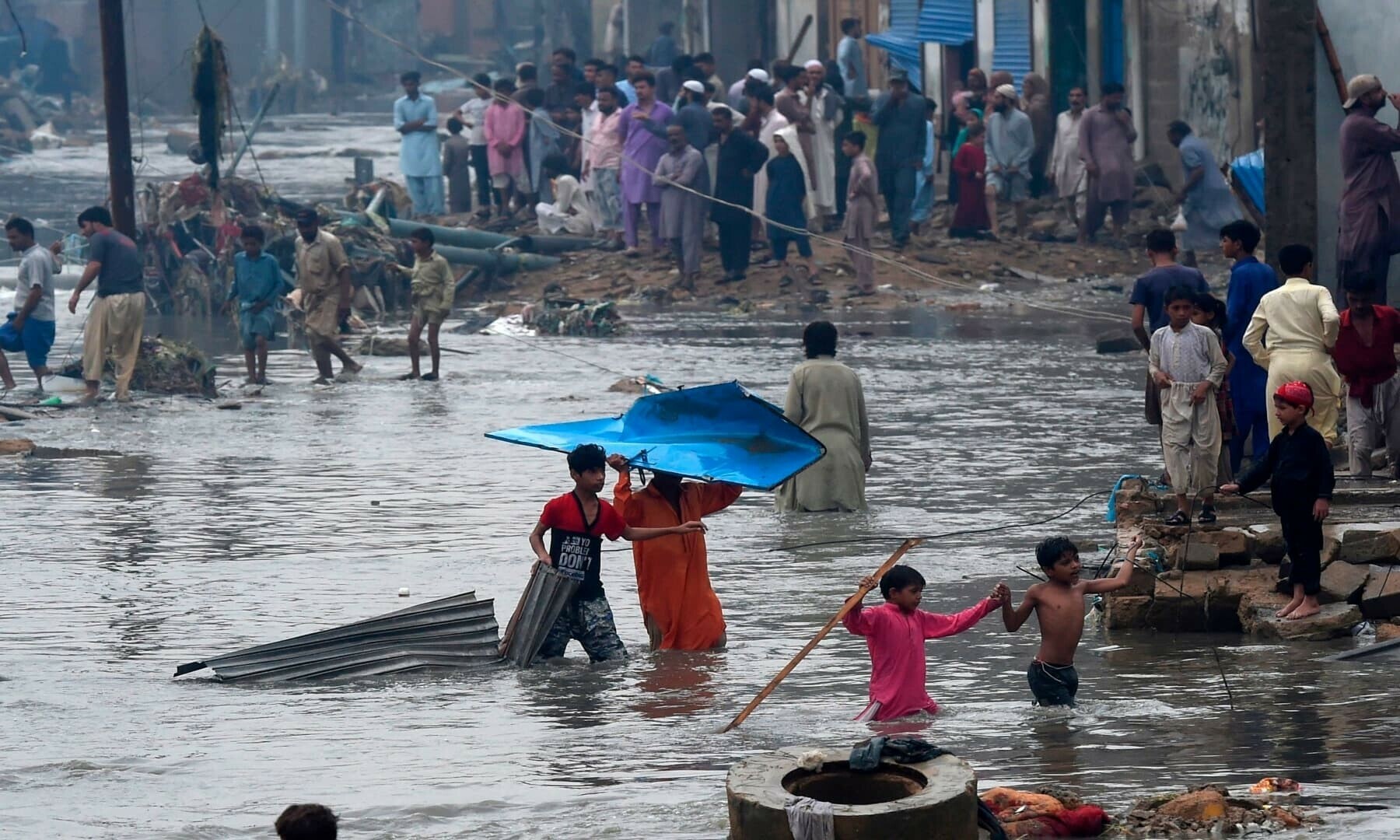People wade through a flooded residential area after heavy monsoon rains in Karachi. &mdash; AFP