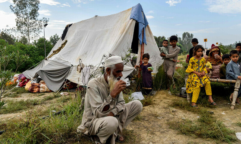 Displaced people take refuge along a highway after fleeing from their flood hit homes following heavy monsoon rains in KP's Charsadda district on Saturday. — AFP