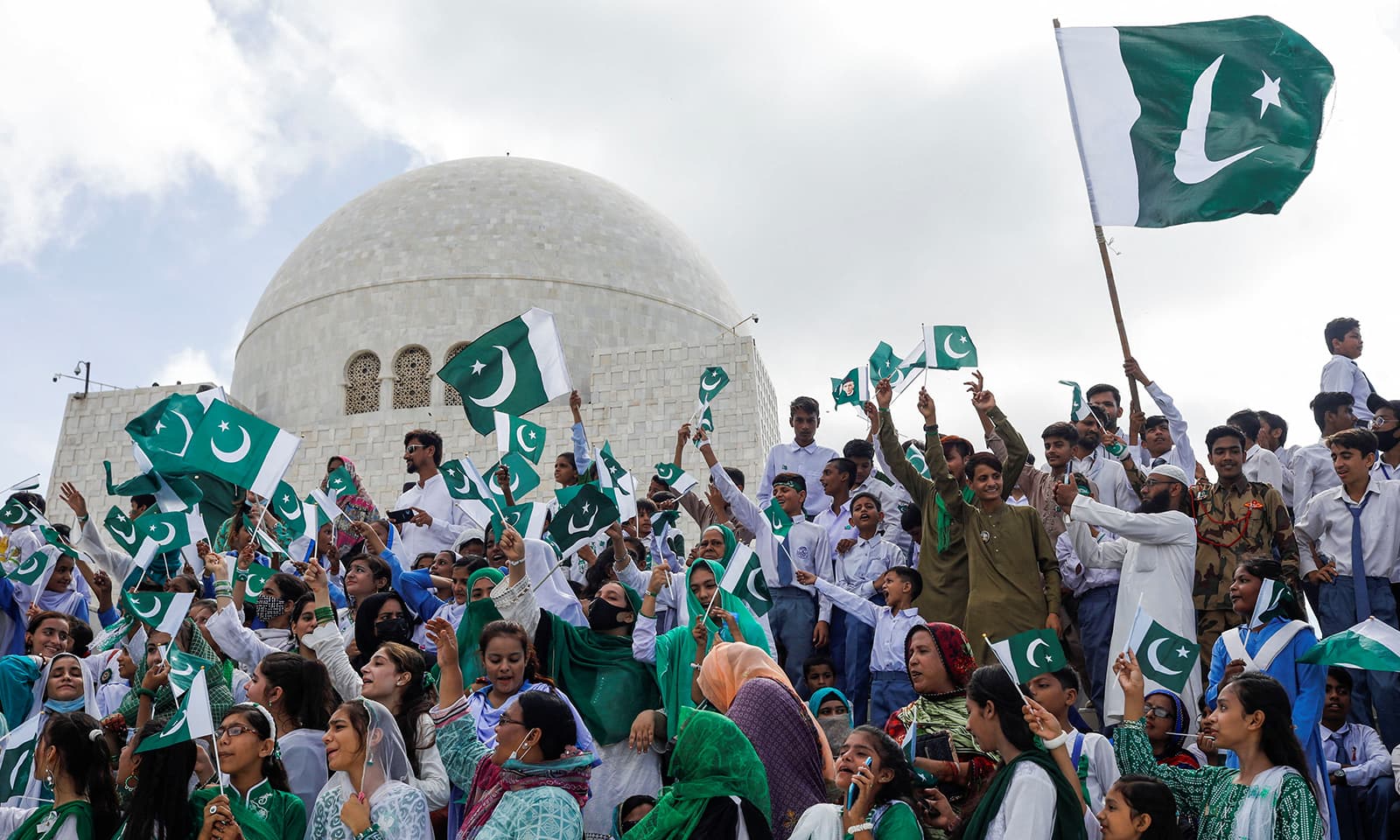 اسکولوں کے بچے اور شہری مزار قائد کے سامنے پرچم لہرا کر ملک کی آزادی کا جشن منا رہے ہیں —فوٹو: رائٹرز