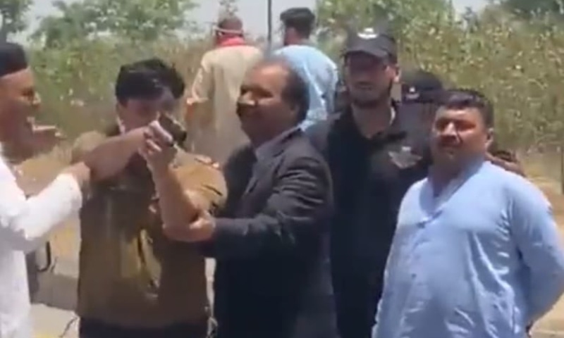 This image purportedly shows a Faisalabad police official pointing a pistol at women protesters. — Photo courtesy: Twitter