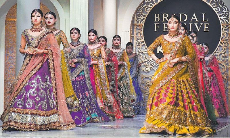 Models wearing bridal dresses walk on the ramp during a fashion show.—Online