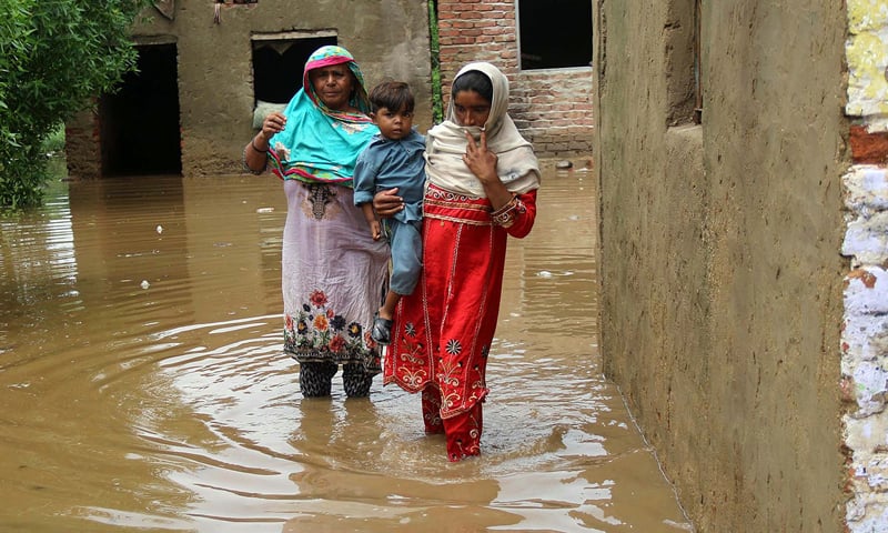 Women, carrying a child, come out of their inundated house in Hyderabad's Muslim Colony on Thursday. — Online