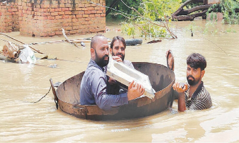 A group of men uses a huge frying pan (karrahi) to cross an affected area in Sukkur on Friday.&mdash;PPI