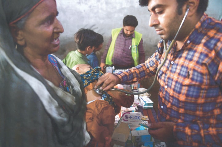 SUKKUR: A doctor examines a four-month-old baby at a medical camp for flood-affected people on the outskirts of the city.—AFP