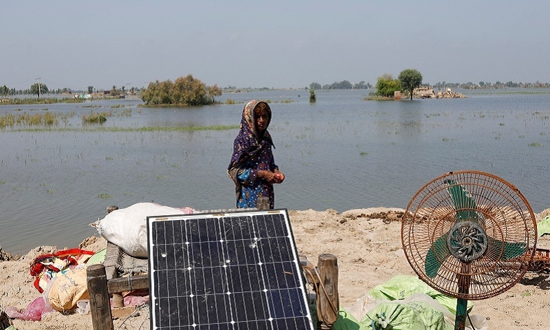 A woman victim of the floods stands with her belongings as she and her family take refuge on higher ground, following rains and floods during the monsoon season in Gari Yasin, Shikarpur, on Wednesday. — Reuters