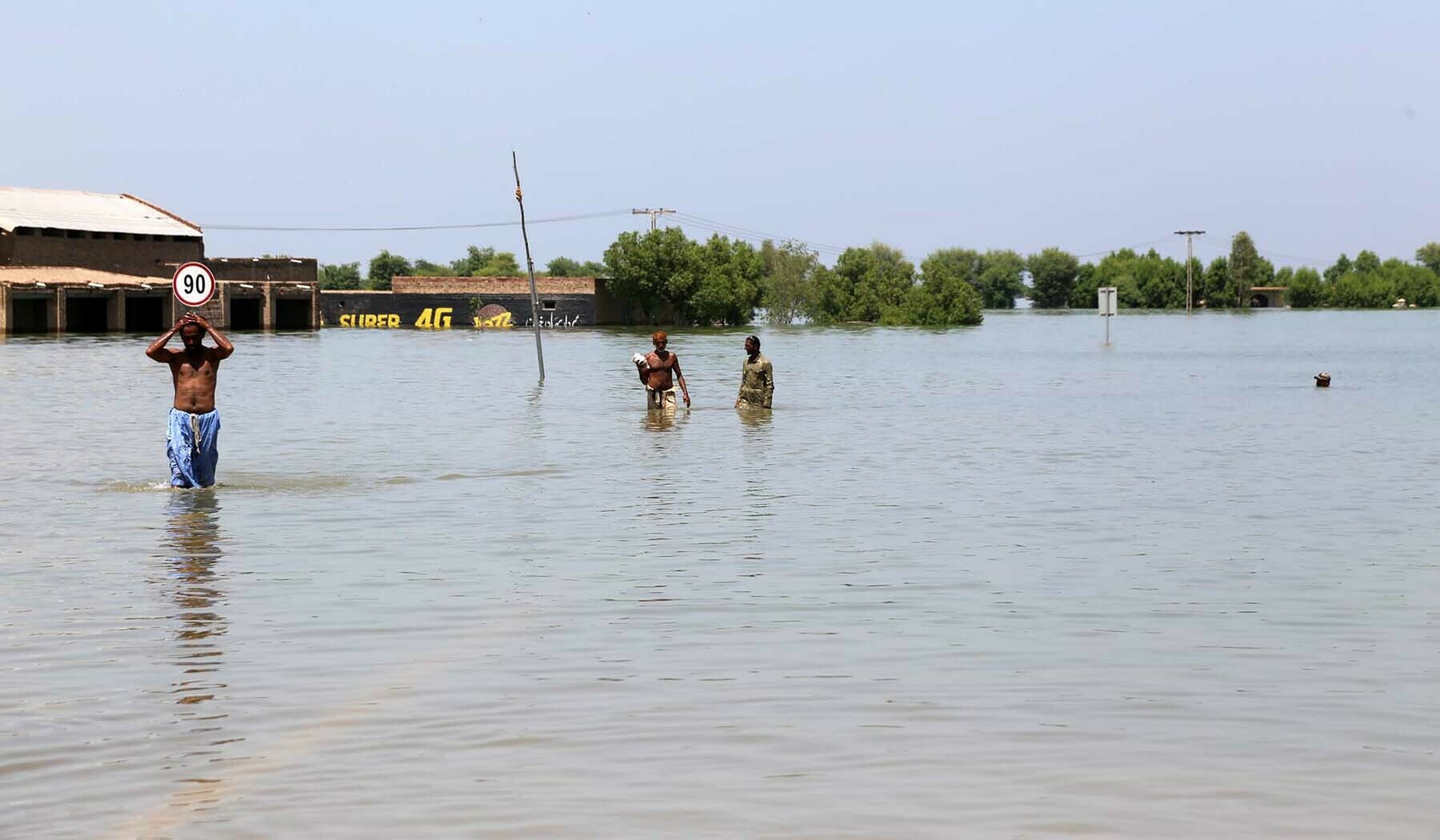 People wade through a flooded road in Khairpur Nathan Shah on Saturday.—Umair Ali