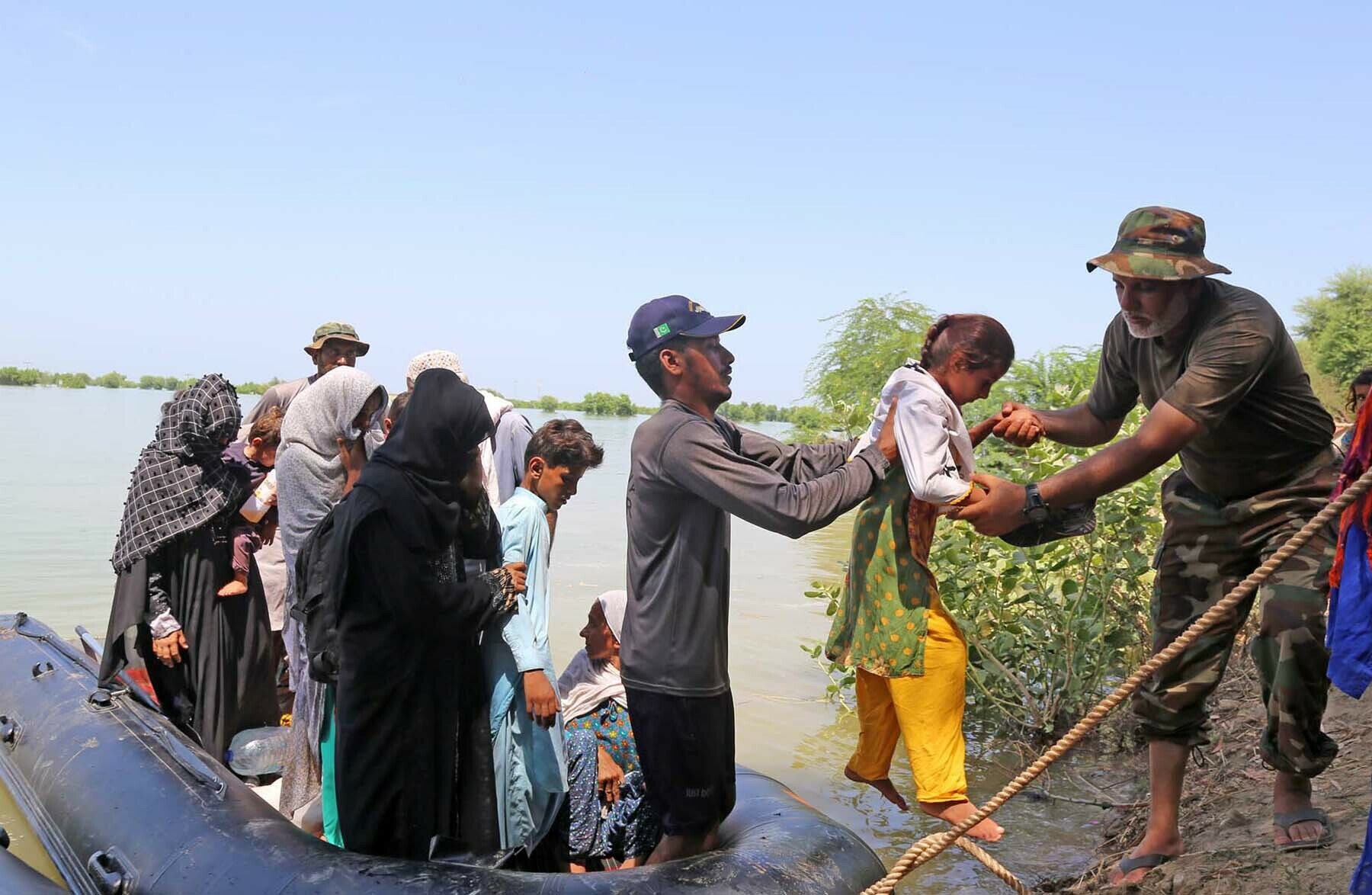 A man helps a girl disembark from a boat after she and others were rescued.—Umair Ali