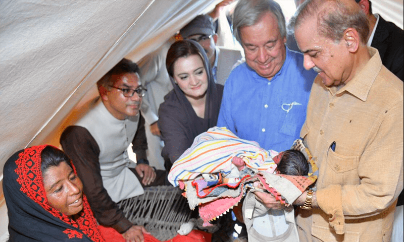 Prime Minister Shehbaz Sharif holds a baby as UN Secretary-General Antonio Guterres looks on at a relief camp on September 10, 2022.—@CMShehbaz