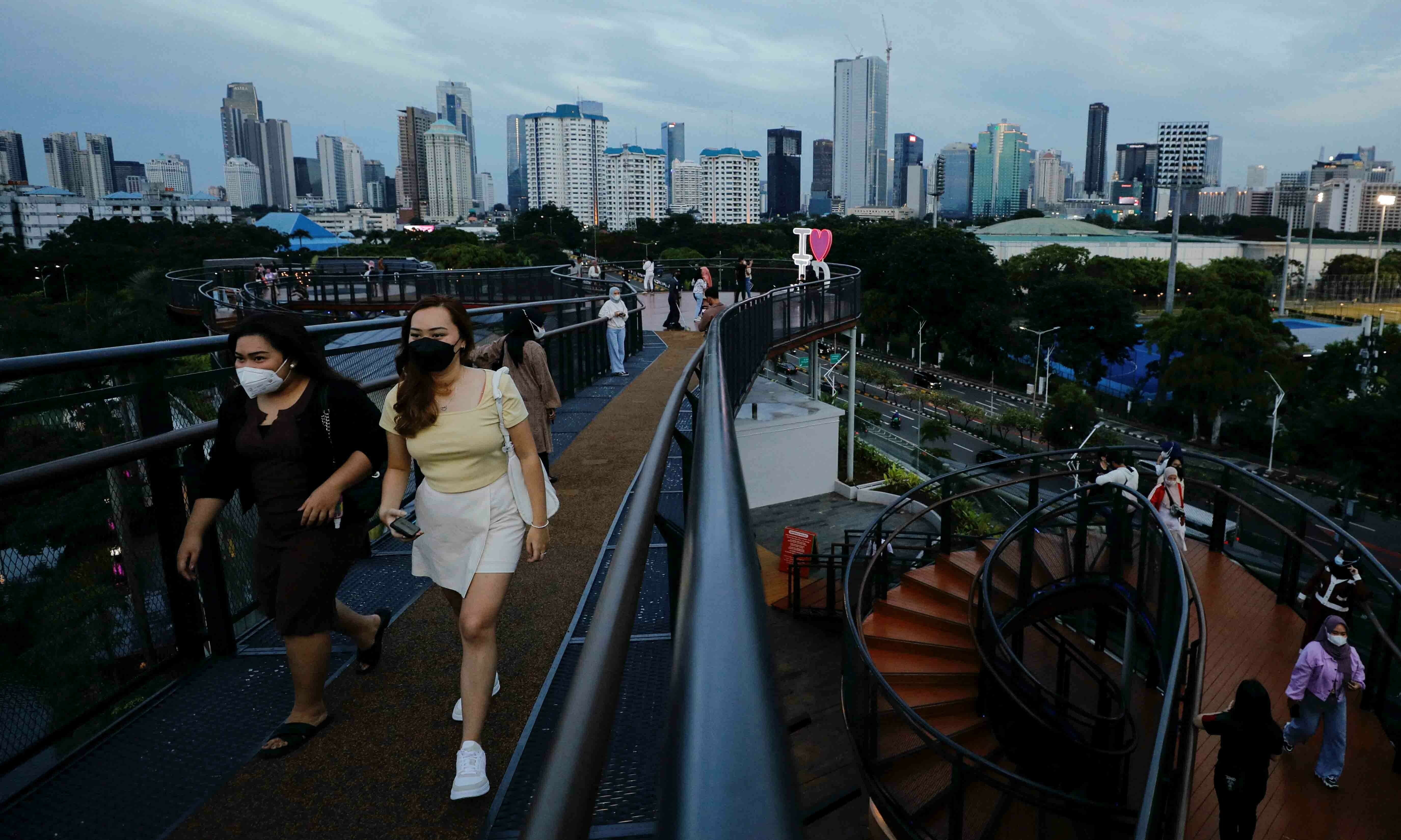 People wearing protective face masks enjoy a stroll along a skywalk bridge as the Omicron coronavirus variant continues to spread, in Jakarta, Indonesia, February 7. &mdash; Reuters