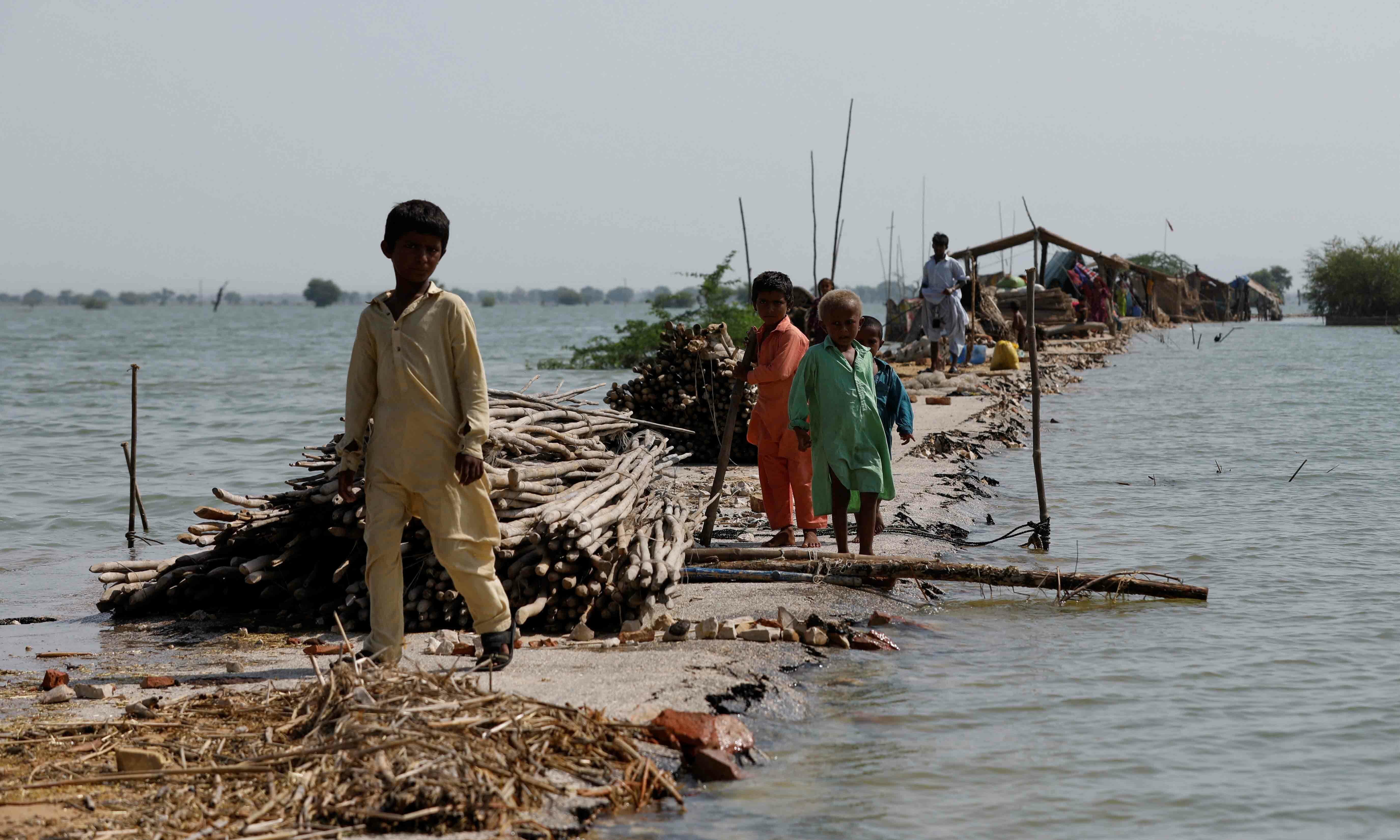 Children stand as their family takes refuge along a damaged road amid flood, following rains and floods during the monsoon season in Bajara village, at the banks of Manchar lake, in Sehwan, on September 6. — Reuters