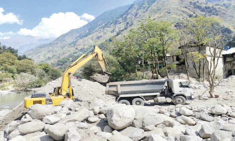 A machine removes the debris to clear the blockage in Kunhar River in Mahandri area of Manoor valley, Mansehra. — Dawn