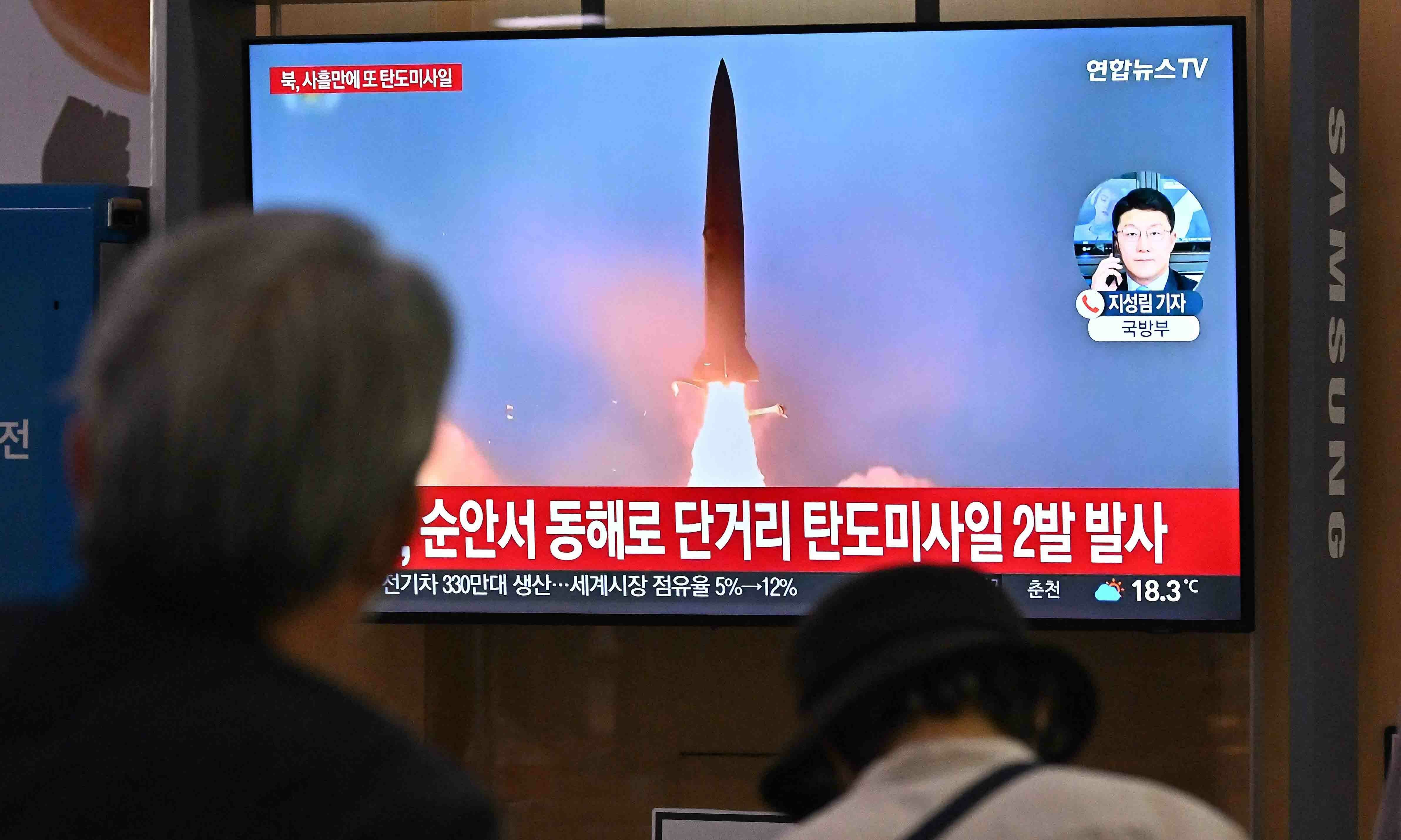 People watch a television screen showing a news broadcast with file footage of a North Korean missile test, at a railway station in Seoul on September 28. — AFP