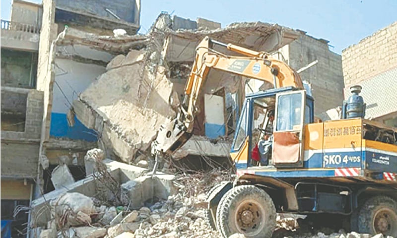 An excavator demolishes houses, said to be constructed illegally, in a district Central locality as part of the ongoing anti-encroachment drive on Friday.&mdash;PPI