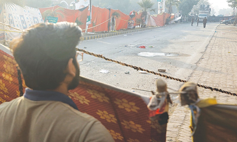 Wazirabad: A man peers through the cordon around the crime scene, where PTI chief Imran Khan’s long march caravan came under attack, on Friday. —Reuters