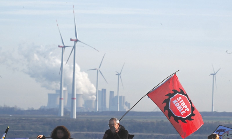 A protester holds a flag reading ‘Stop Coal’ in front of the coal-fired power plant Neurath during a demonstration at the Garzweiler lignite open cast mine near Luetzerath on Saturday.—AFP