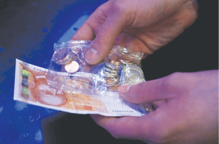 A man holds 100 kunas and a package containing euros in Zagreb, Croatia. With inflation mounting and precarious geopolitical headwinds rattling Europe, Croatia hopes that its upcoming switch to the euro will bring some semblance of protection to the Balkan country in an uncertain world.—AFP