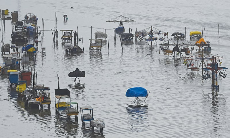 Chennai: People stand in a flooded area of Marina beach following the cyclonic storm Mandous. — AFP Chennai: People stand in a flooded area of Marina beach following the cyclonic storm Mandous. — AFP