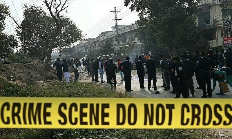 Policemen gather at the suicide blast site in Islamabad on Dec 23. — AFP