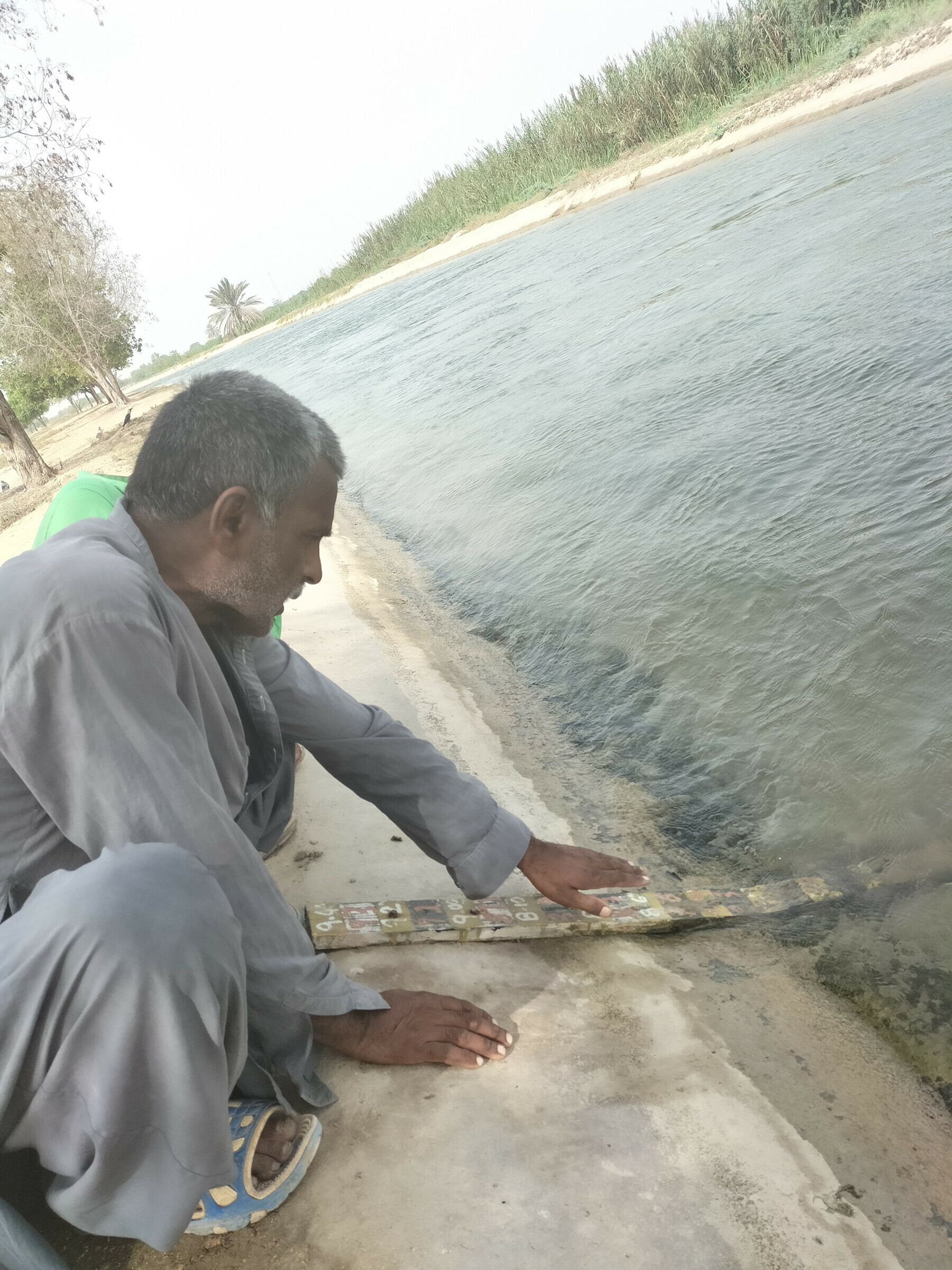 KWSB employee at the Keenjhar-Gujjo canal showing the water gauge.