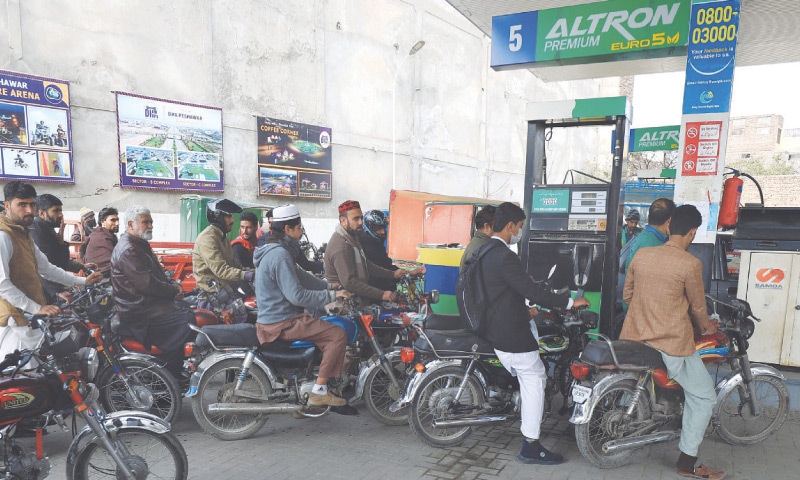 PESHAWAR: People wait for their turn to get fuel at a petrol station.—Reuters / file