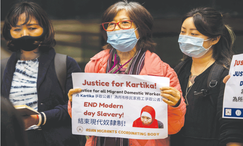 Esther Bangcawayan (centre), from the Asian Migrants Coordinating Body, holds a sign outside Wan Chai district court in Hong Kong on Friday.&mdash;AFP