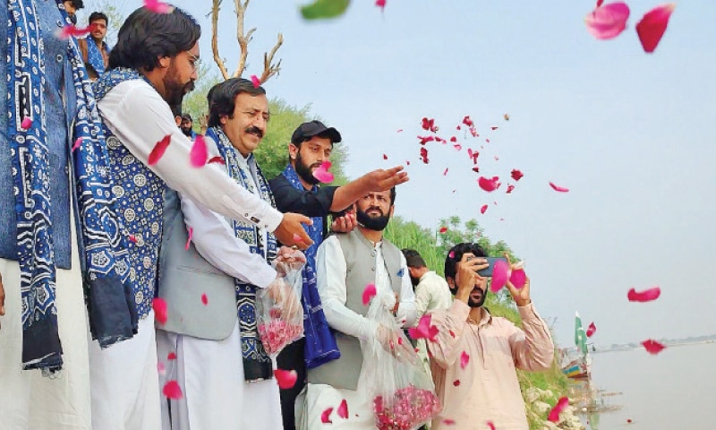People throw petals in the Indus River on Sunday. — Dawn People throw petals in the Indus River on Sunday. — Dawn