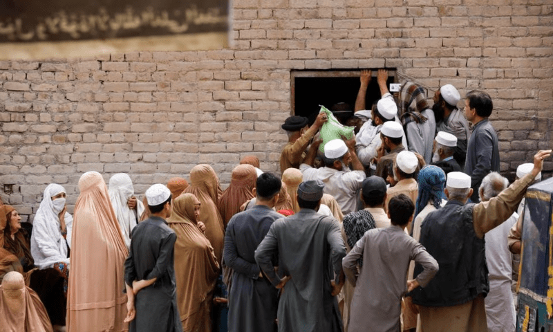 People gather to receive sacks of free flour, at a distribution point in Peshawar, Pakistan March 30, 2023. — Reuters