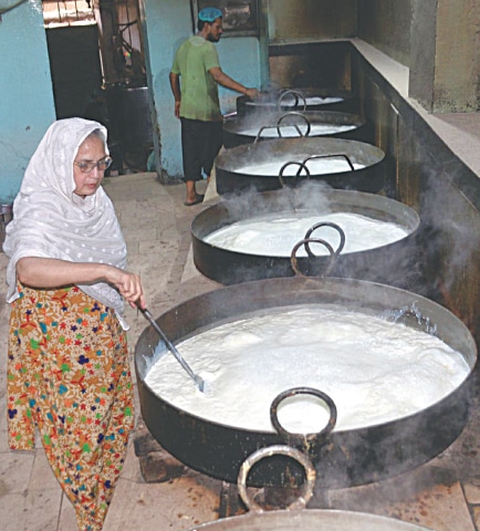 Naseem Bano stirs the milk being boiled to prepare rabri.&mdash;Dawn