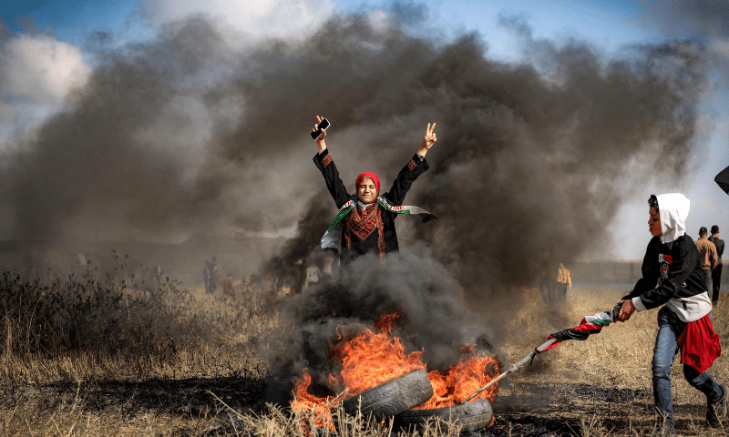 A woman gestures as she stands by flaming tires during a Palestinian &lsquo;flag march&rsquo; demonstration along the border with Israel east of Gaza city on May 18, 2023 in response to the annual Israeli flag march marking &lsquo;Jerusalem Day&rsquo; commemorating the old city&rsquo;s capture by Israel. &mdash; AFP